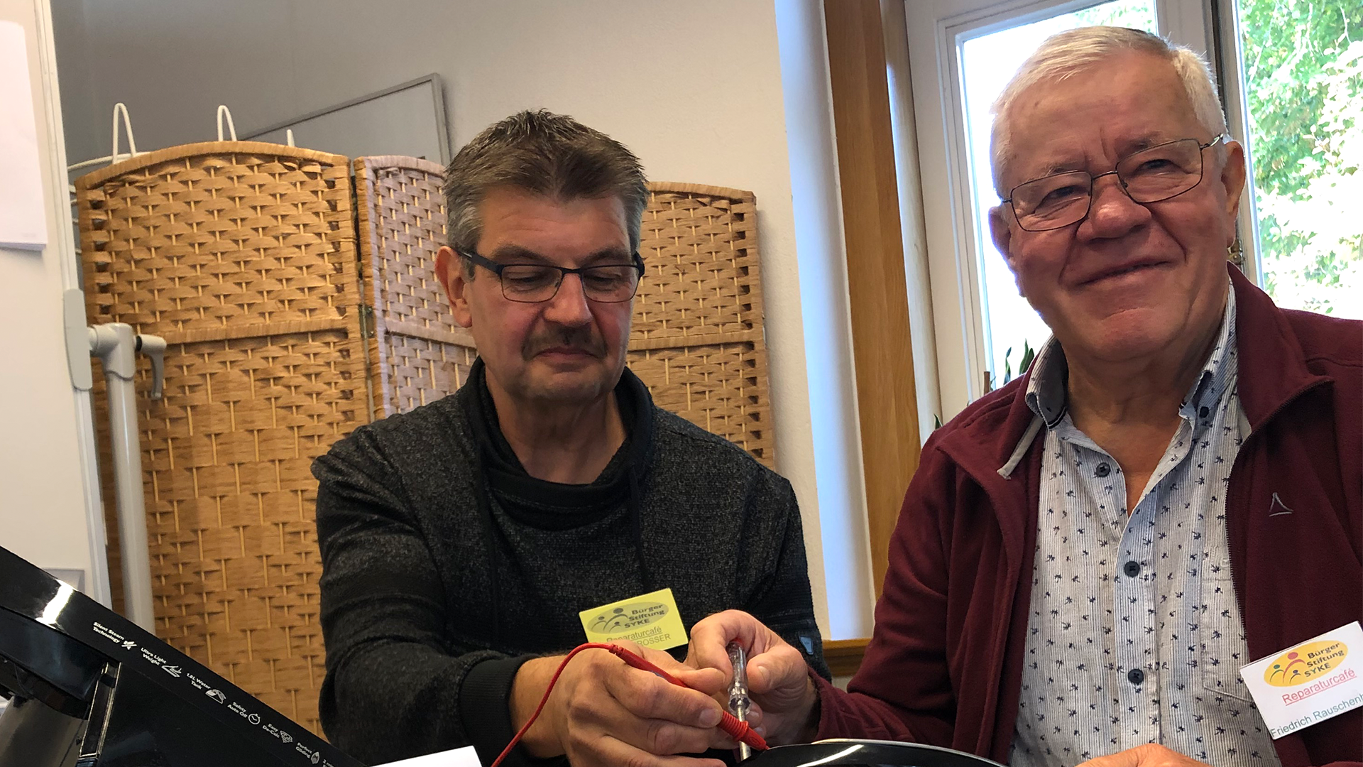 Zwei Personen reparieren ein Elektrogerät.