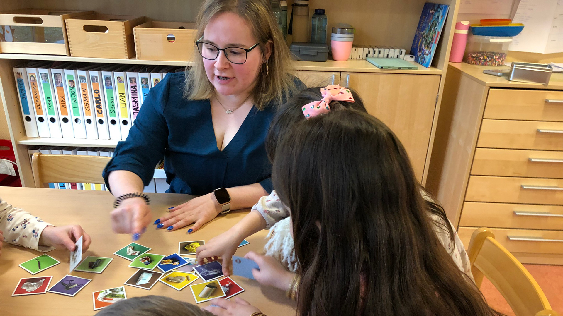 Eine Erzieherin der Kita Bullerbü zeigt Kindern die magnetischen Memory-Karten.