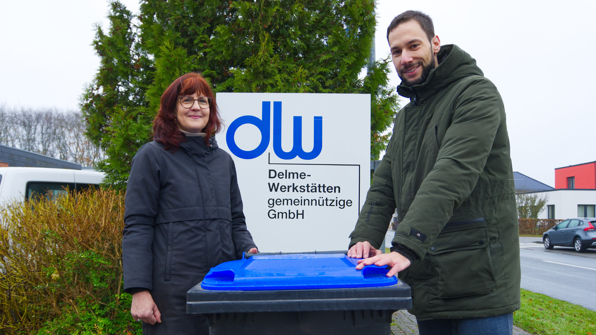 Vertreter der Delme-Werkstätten und der AWG Bassum stehen an einer blauen Tonne.